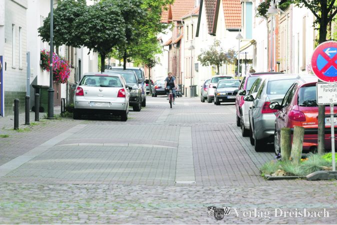 Beispiel Gonsenheim, zufälligerweise die Schulstraße: Die Mainzer arbeiten mit farblichen Trennungen und achsenunfreundliche Erhebungen, die auch potenziell Uneinsichtigen das Langsamfahren ratsam erscheinen lassen. Die Gonsenheimer Schulsraße als direkte Parallelstraße zur Hauptverkehrsachse des Stadtteils noch näher dran am großen Verkehr als die Bischofsheimer Schulstraße, aber dennoch nur wenig befahren.