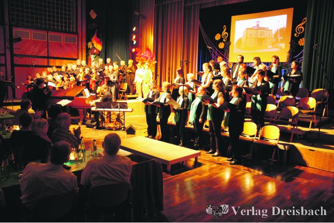 Die „Happy Voices“ (vorne) und der Gemischte Chor der Germania boten im Bürgerhaus zwei Stunden lang ein unterhaltsames Programm, das sich um eine Tourneereise der Bischofsheimer Sänger drehte.