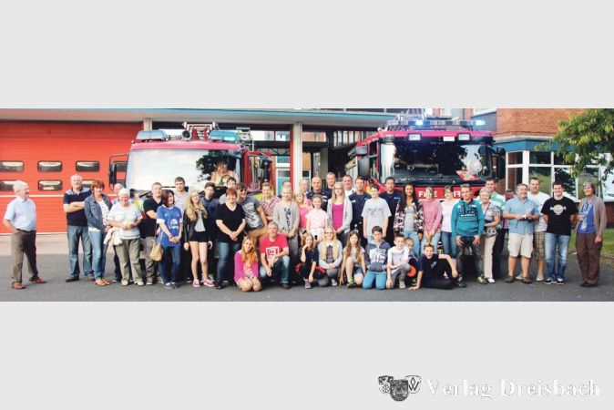 Die Bischofsheimer Nachwuchs-Brandsch&uuml;tzer, in Zivil und vermischt mit den Gastgebern auf einem Foto vereint. Im Hintergrund die Fahrzeughalle in Crewe und zwei Einsatzfahrzeuge der britischen Kollegen.

&nbsp;