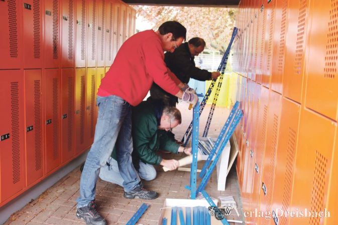 Die blauen Regale, die hier so effektvoll zwischen den orangefarbenen Spinden zusammengebaut wurden, sind f&uuml;r den neuen kleinen Lagerraum des FFHA bestimmt.