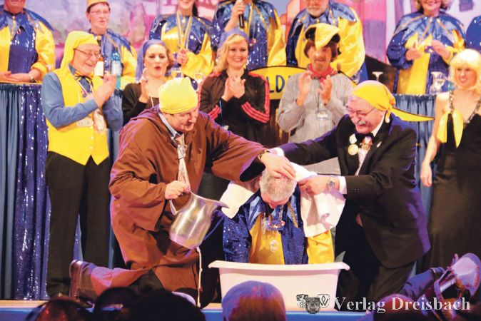 So wird man(n) zum K&uuml;mmeldrescher: Der Okrifteler Wolfgang Drescher erh&auml;lt die traditionelle Taufe mit Mainwasser von Heribert Franssen (links) und Bernd Seel.