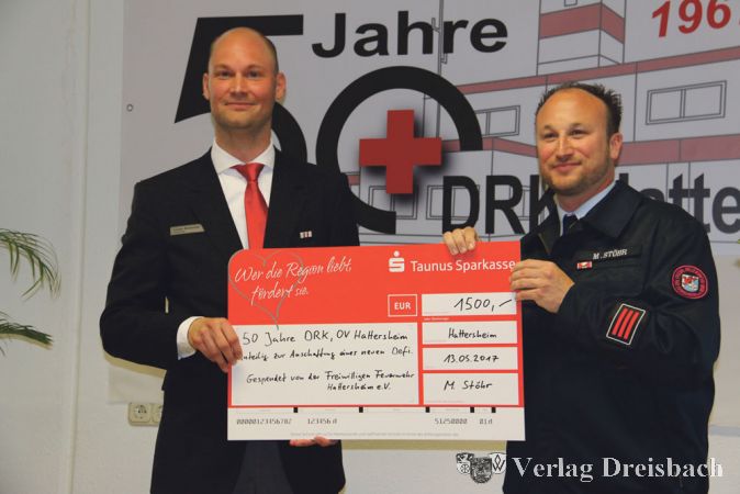 Einen &bdquo;dicken&ldquo; Scheck hatte der Vorsitzende der Freiwilligen Feierwehr Hattersheim, Markus St&ouml;hr (rechts), f&uuml;r seine Kameraden vom DRK mitgebracht.