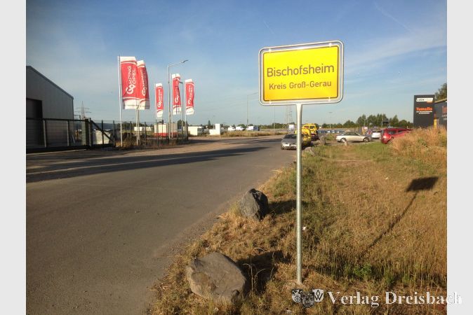 Zwar führt die Zufahrt zur "Tagweide" durch das Gustavsburger Gewerbegebiet "Flurgraben", dennoch ist das Areal westlich der A671 und südlich des Gustavsburger Gewerbegebiets Bischofsheimer Ortsgebiet, wie inzwischen auch ein Ortsschild an der Erschließungsstraße belegt.