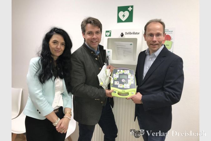 Dr. Daniela Kliesch, Bürgermeister Thies Puttnins-von Trotha und Dr. Ulrich Jantzen (v.l.) präsentieren den Defibrillator im Bürgerbüro Ginsheim.