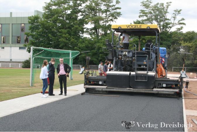 Von links nach rechts: Celia Volk und Katharina Keib vom Amt für Grünflächen begutachten gemeinsam mit dem Ersten Beigeordneten Franz Jirasek die Arbeiten auf dem Sportplatz.