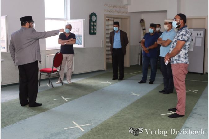 Imam Athar Sohail erläutert Bürgermeister Dr. Bernd Blisch (v. l.) das Abstandskonzept im Gebetsraum, der mit abgeklebten Kreuzen die Positionen der Betenden vorgibt. Weitere Gesprächspartner Blischs waren der Gemeindevorsitzende der Ahmadiyya in Flörsheim, Naveed Ahmad, der Vorsitzende der Jugendorganisation, Mahmood Kahloon, der Sekretär für die Öffentlichkeitsarbeit Munawar Abid und der Sekretär für die Außenangelegenheiten, Amir Naz.