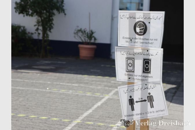 Vor der Moschee wird den Besuchern die ATA-Regel erklärt: Aufsetzen der Maske, Teppich mitbringen, Abstand halten.