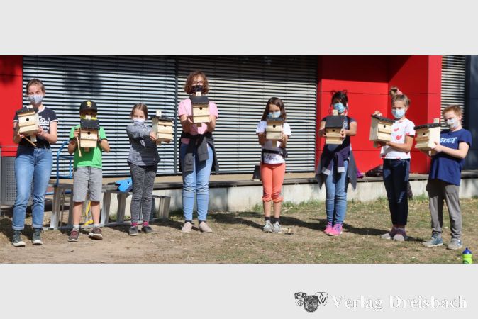 Acht Schülerinnen und Schüler der Umwelt-AG der Sophie Scholl-Schule präsentieren die Nistkästen, die inzwischen an Bäumen auf dem Schulgelände verteilt zu finden sind.