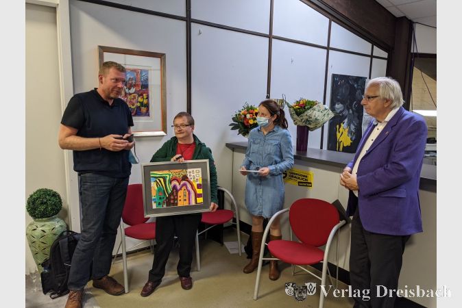 Ulrich Mann (Geschäftsführer Lebenshilfe Main-Taunus, links), David Ernst und Jenny Hillebrandt überreichen Kurt-Jochem Graulich (rechts) ein Bildpräsent als Dankeschön für den Stiftungspreis.