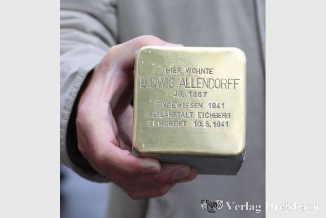 Allendorff mit zwei "F". Der Name des durch die Verlegungsaktion im Juni 2019 gewürdigten Ludwig Allendorff in der Hauptstraße 12 war aufgrund der dem Verein vorliegenden Dokumente nicht korrekt, wie sich im Nachhinein herausstellte. Klaus-Peter Harth präsentiert hier den neuen Stein, den der Verein Stolpersteine Flörsheim anfertigen ließ..