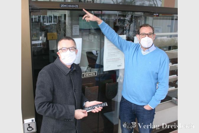 Erster Beigeordneter Franz Jirasek (links) und Bürgermeister Christian Seitz (rechts) beim Anbringen des Segensspruch-Aufklebers über dem Eingang des Rat- und Bürgerhauses.