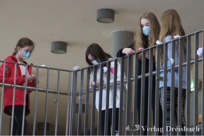 Knapp 50 weiße, selbstgebastelte Papierrosen erinnern am Geländer des Foyers an den 100. Geburtstag der Namensgeberin der Sophie-Scholl-Schule.