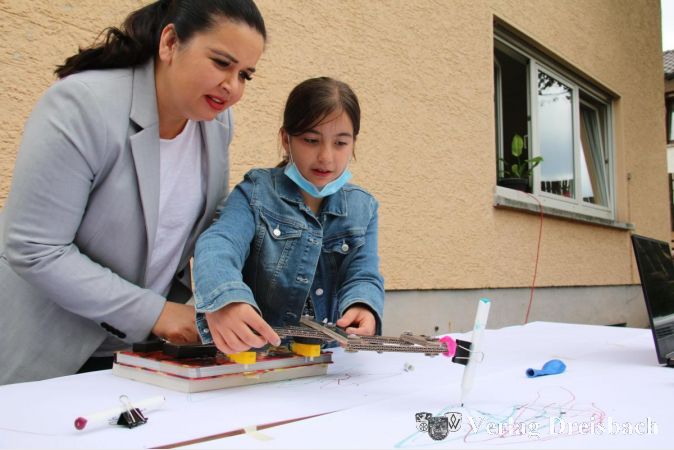 Yalda zeigt ihrer Mutter, wie der von den Kindern gemeinsam gebastelte Malroboter funktioniert.