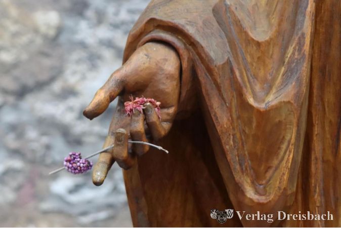 Sogar Blumenschmuck trägt die Holzfigur mitten im Winter.