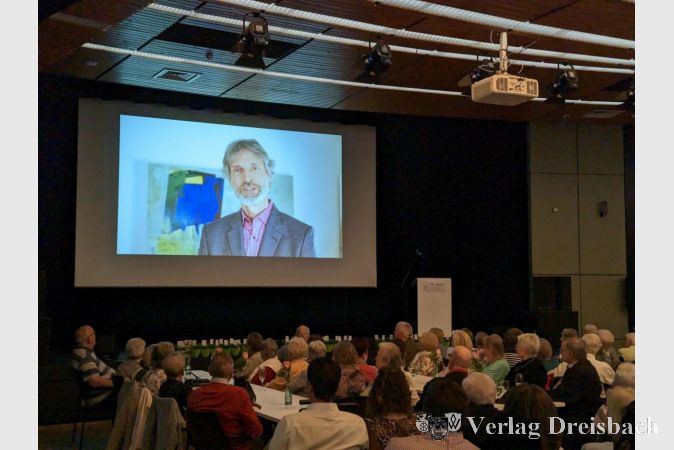 Filmpremiere in der Stadthalle: Zum Jubiläum blickte die Hawobau in bewegten Bildern auf ihre Geschichte zurück und ließ langjährige Anwohnerinnen und Anwohner zu Wort kommen. Geschäftsführer Holger Kazzer (hier im Bild) erläuterte unter anderem das Selbstverständnis der Gesellschaft.