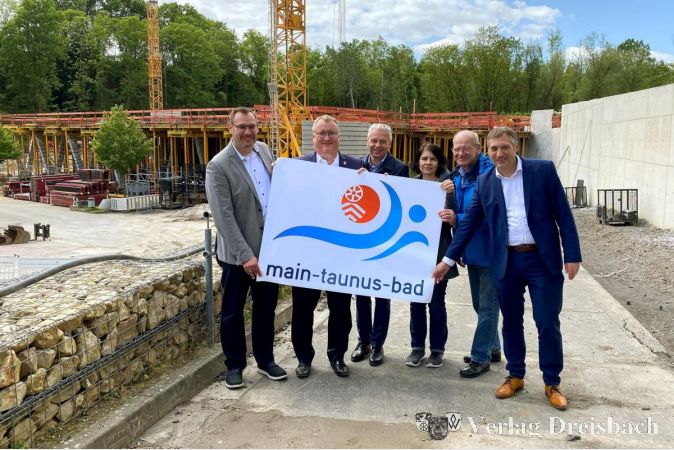 V.l.n.r.: Die Bürgermeister Seitz und Schindling, Landrat Cyriax, die Schulleiterin Kippel, der Sportkreisvorsitzende Böhl und Kreisbeigeordneter Fink bei der Vorstellung des künftigen Hallenbad-Logos.