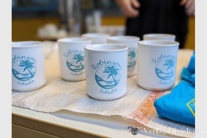 Am Merchandise-Stand der Schule gab es neben den beliebten blauen T-Shirts auch schicke Tassen mit dem Schullogo.