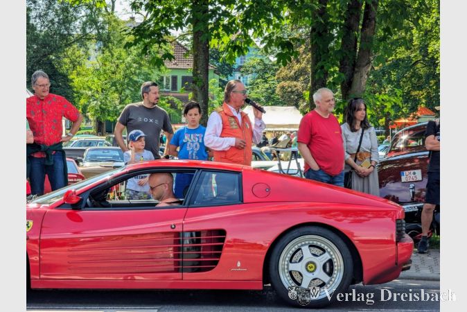 Moderator Bernd Schultz vor einem Ferrari Testarossa, den er gerade - wie alle anderen Fahrzeuge auch - willkommen geheißen hat.