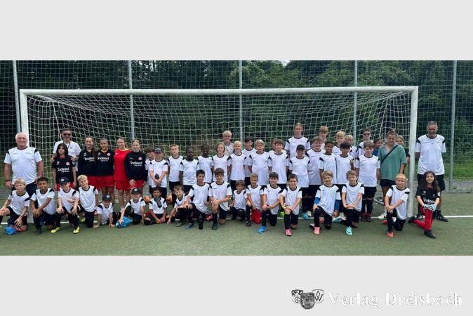 Kinder und ihre Trainer versammeln sich zum Gruppenfoto, um den erfolgreichen Abschluss des Fußballcamps der DJK Flörsheim zu feiern.