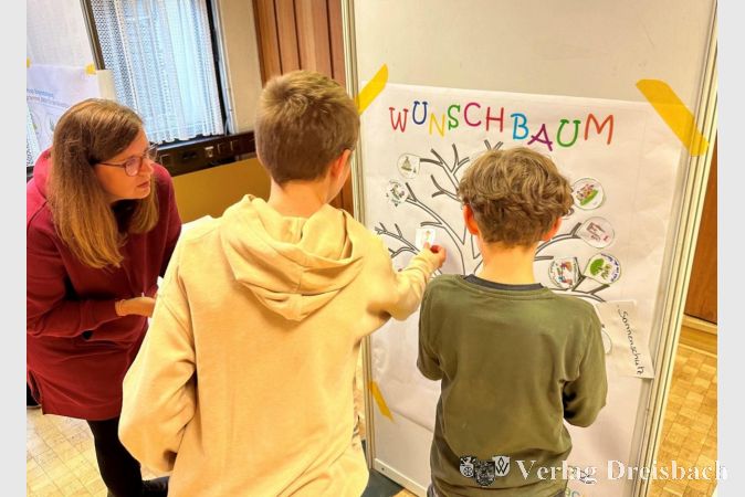 Kinder platzierten ihre Vorstellungen zum Spielplatz auf dem "Wunschbaum". Links im Bild Tanja Seitz, die stellvertretende Leiterin des evangelischen Kindergartens Vogelnest und Vorsitzende des Kinderparlaments.