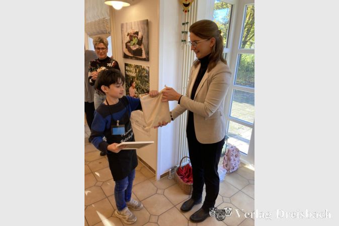 Luis erhält seine Ernennungsurkunde und ein Geschenk von Heike Seibert.