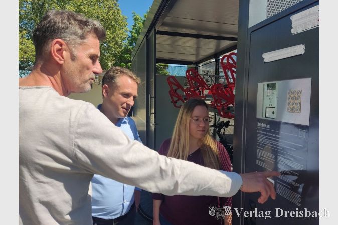 Bauamtsmitarbeiter Michael Knittel (links) und die Klimaschutzmanagerin Melanie Laier mit dem Ersten Beigeordneten Martin Mohr beim Ausprobieren der Fahrradsammelschließanlage.
