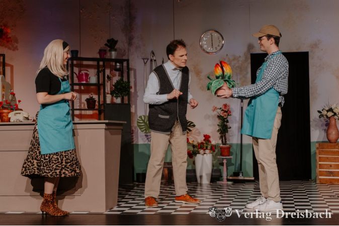Audrey (Nina Wolf), Mr. Mushnik (Hartmut Opfermann) und Seymour (Niklas Schliesmeier) bestaunen die merkwürdige neue Pflanze