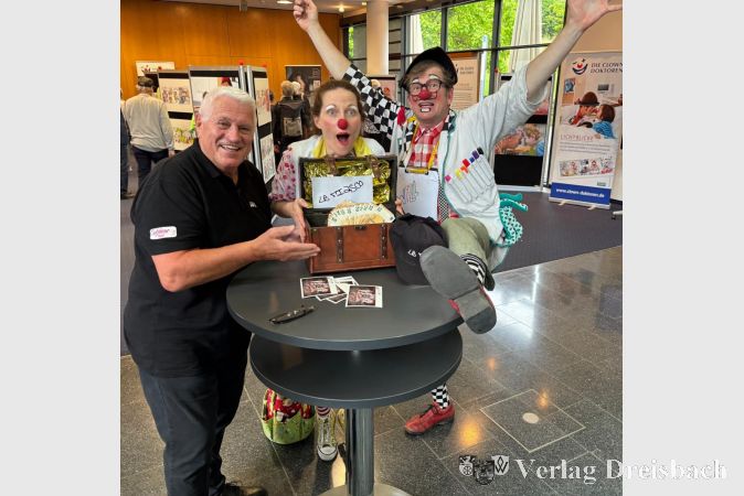 Wilfried Beese von der KKK-Gruppe Le Fiasco übergibt in Wiesbaden 555 Euro an zwei fröhliche Clowndoktoren