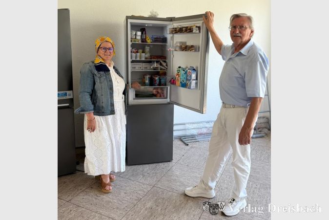 Sozialarbeiterin Semiha Eroglu-Buch und Integrationslotse Norbert Meerwald vor einem Kühlschrank im neuen Raum, in dem Obdachlose Zugriff auf gerettete Lebensmittel haben.