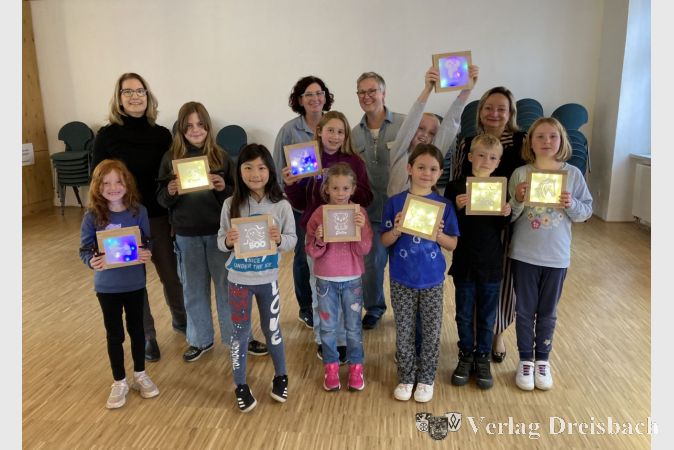 Stolz zeigen die Teilnehmerinnen und Teilnehmer des Workshops „Kreativ mit Klötzchen und Plotter“ ihre fertigen Lampen. Die Erwachsenen im Hintergrund sind Heike Seibert, Christine Gesang, Patricia Jung und Anastassia Tanopoulou (von links).