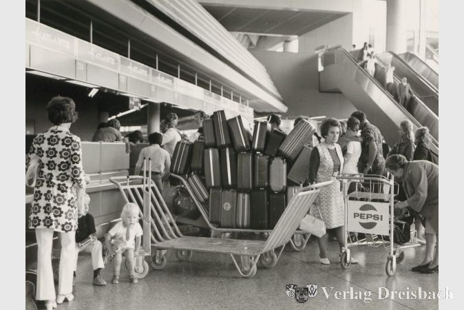 Passagiere mit Gepäckwagen und Kofferkulis (ältere Modelle) am Counter 724, Terminal 1.