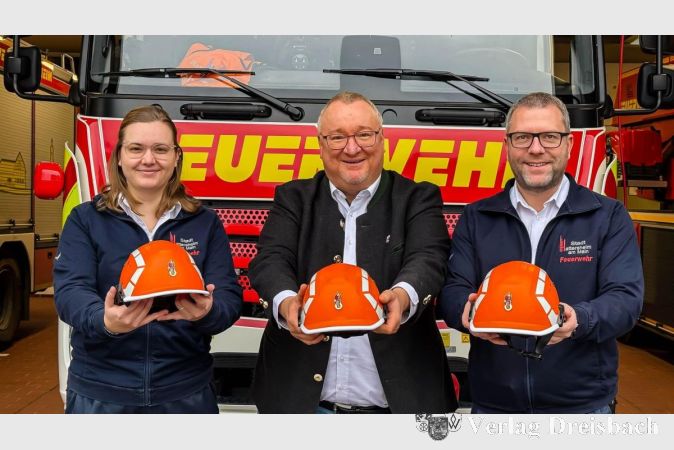 Stadtjugendfeuerwehrwartin Svenja Baum, Bürgermeister Klaus Schindling und Stadtbrandinspektor David Tisold präsentieren die neuen Helme.