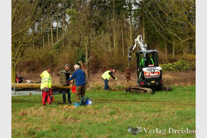 Foto: privat
Während Bernd Zürn (blauer Pullover) mit zwei Helfern den Turmfalkenkasten an der Mastspitze befestigt, wird im Hintergrund das Standloch gebohrt.