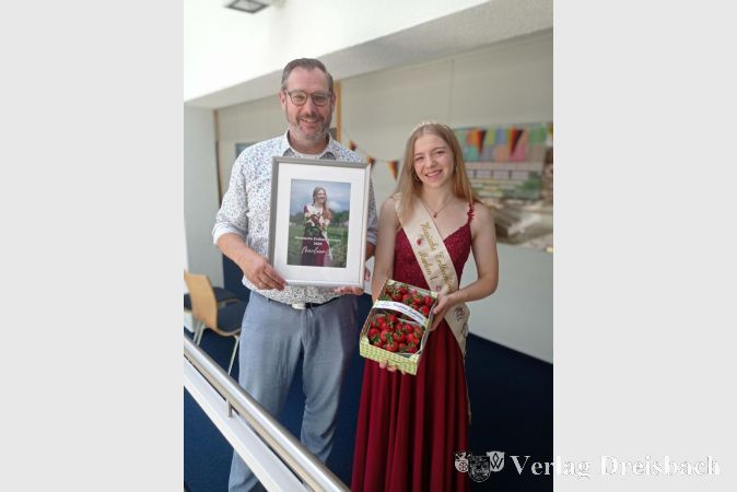 Foto: Gemeinde
Bürgermeister Christian Seitz zeigt Erdbeerkönigin Marleen I. das Foto, das nun im Rathausflur hängt.