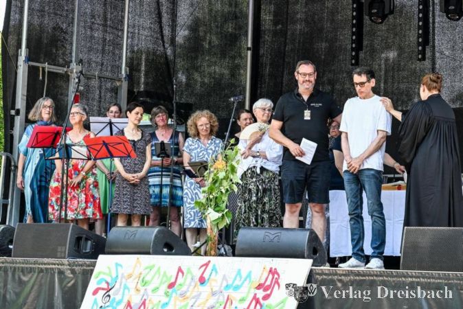 Foto: FFC/Thomas Wiegand
Thomas Milkowitsch wird für seine neuen Aufgaben als Bürgermeister von Schwalbach gesegnet. Von rechts: Pfarrerin Melanie Khalil, Thomas Milkowitsch und Christian Seitz. Links der Chor für Neue Geistliche Lieder (NGL).